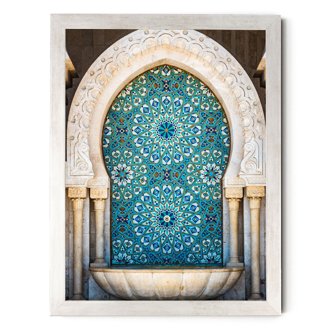 a large, ornate archway with intricate blue and white tile patterns. The archway is framed in white and is set within a stone wall. The overall composition of the image is visually striking and showcases the architectural beauty of the structure.