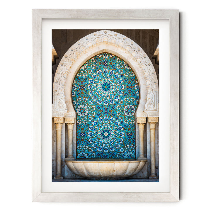 a large, ornate archway with a blue and white patterned tile design. The archway is framed in a white border and is set within a stone wall.