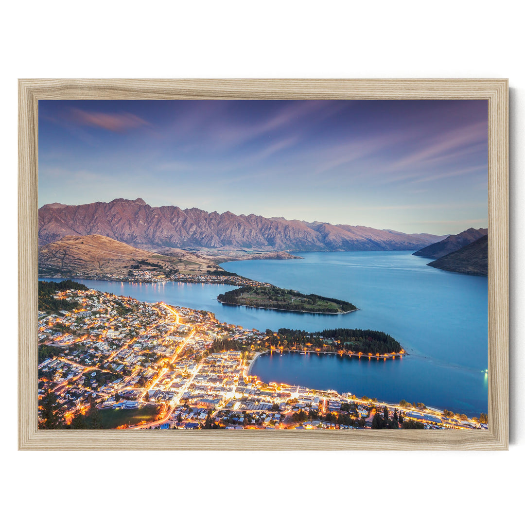 a picturesque city nestled at the foot of a mountain range, with the city's lights twinkling against the backdrop of the mountains and the deep blue lake.