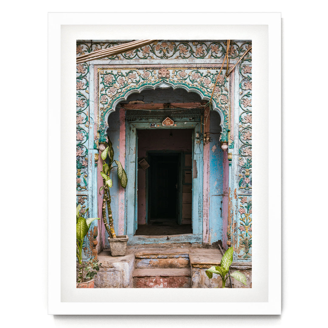 a colorful, ornately decorated doorway with a blue and green color scheme, surrounded by lush greenery and plants.
