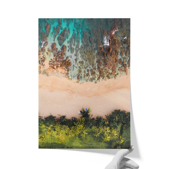 The image is a vibrant aerial view of a tropical beach, showcasing a sandy shoreline, lush palm trees, and a clear blue sky.
