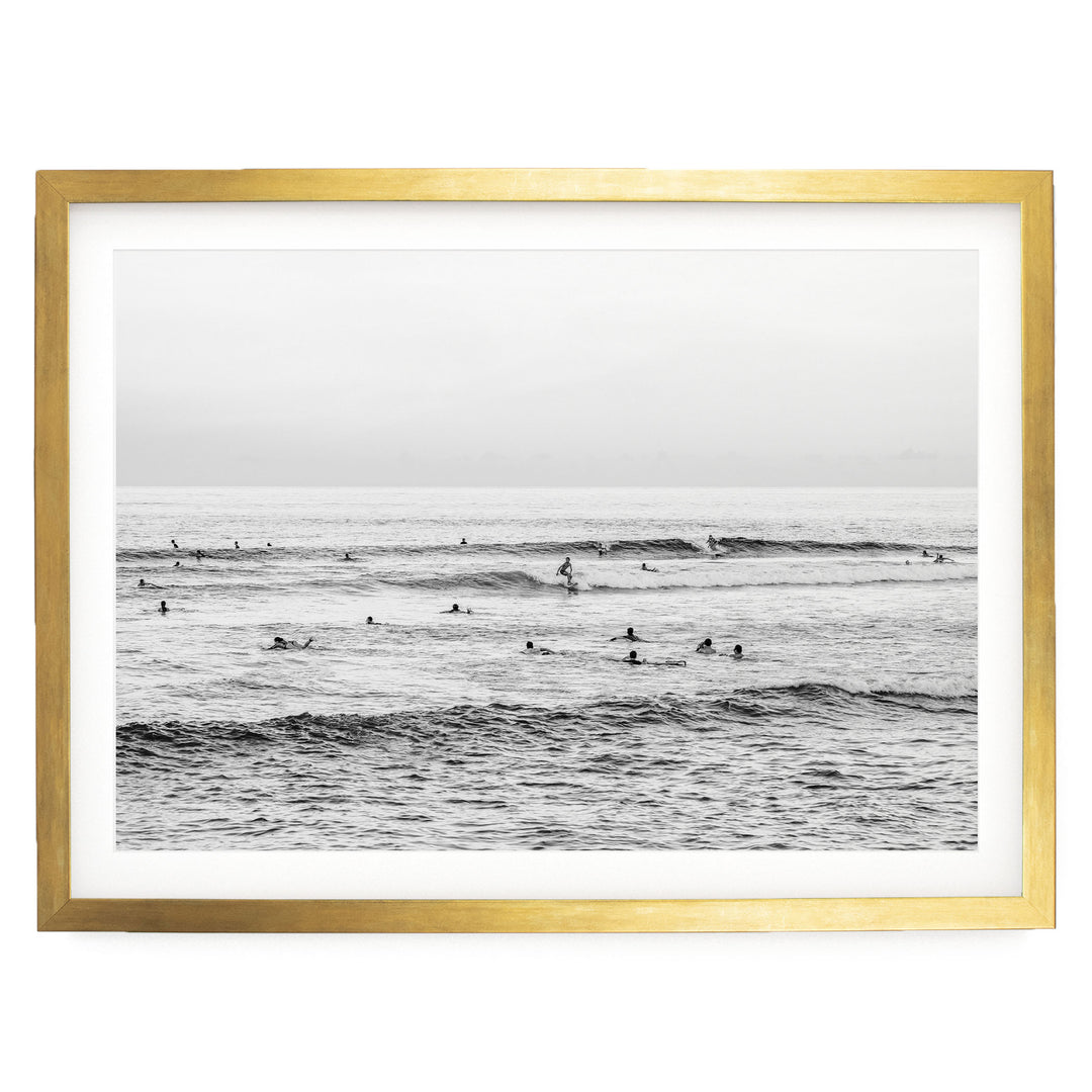 A black and white photograph of a group of people swimming in the ocean, with waves visible in the background.