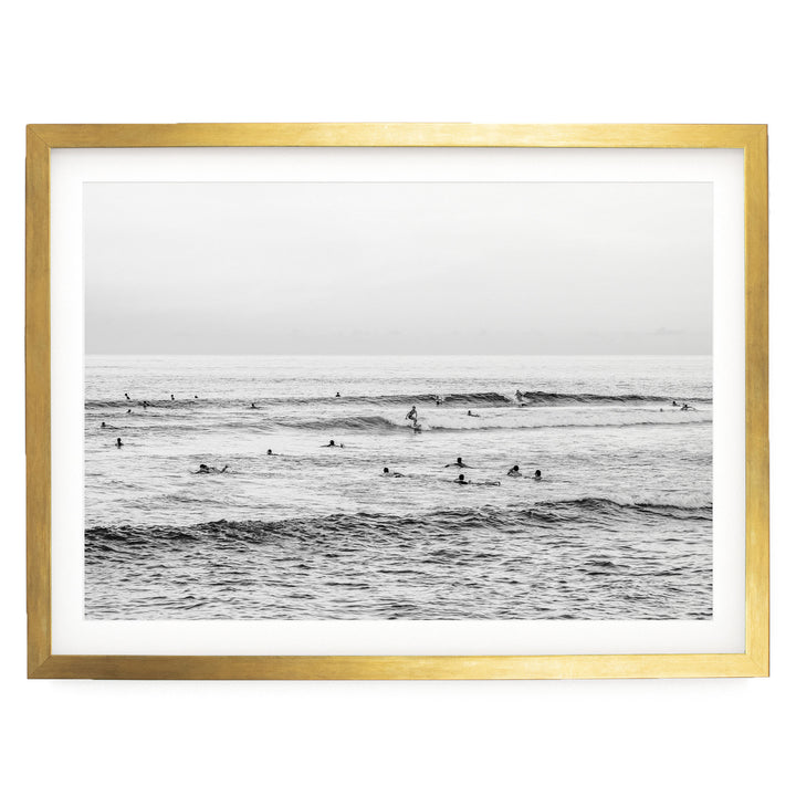 A black and white photograph of a group of people swimming in the ocean, with waves visible in the background.