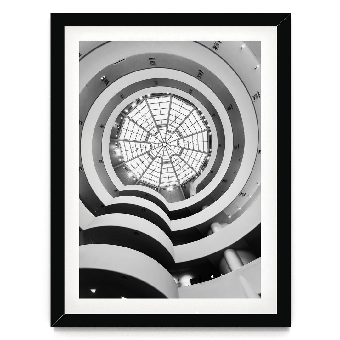 A black and white photograph of a spiral staircase with a large circular glass dome at the top, creating a striking visual effect.