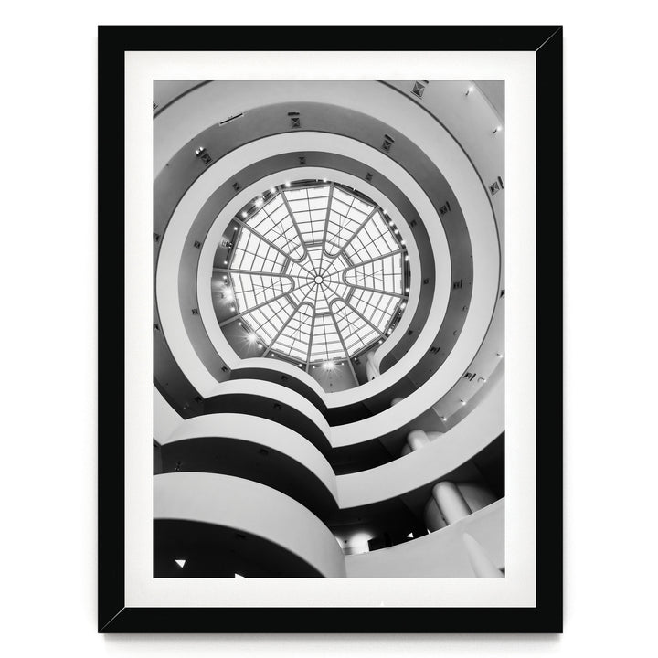 A black and white photograph of a spiral staircase with a large circular glass dome at the top, creating a striking visual effect.