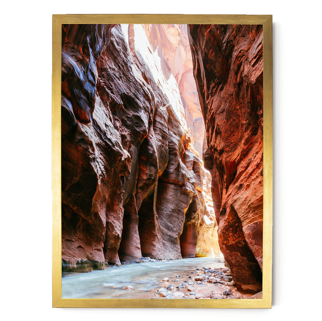 A framed photograph depicting a narrow, winding river flowing through a canyon with towering red rock walls on either side.