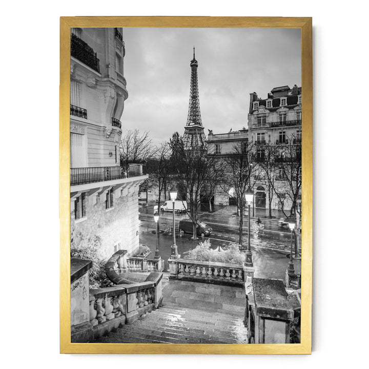 The image is a black and white photograph of the Eiffel Tower in Paris, France, with a street scene in the foreground featuring ornate buildings and lampposts.