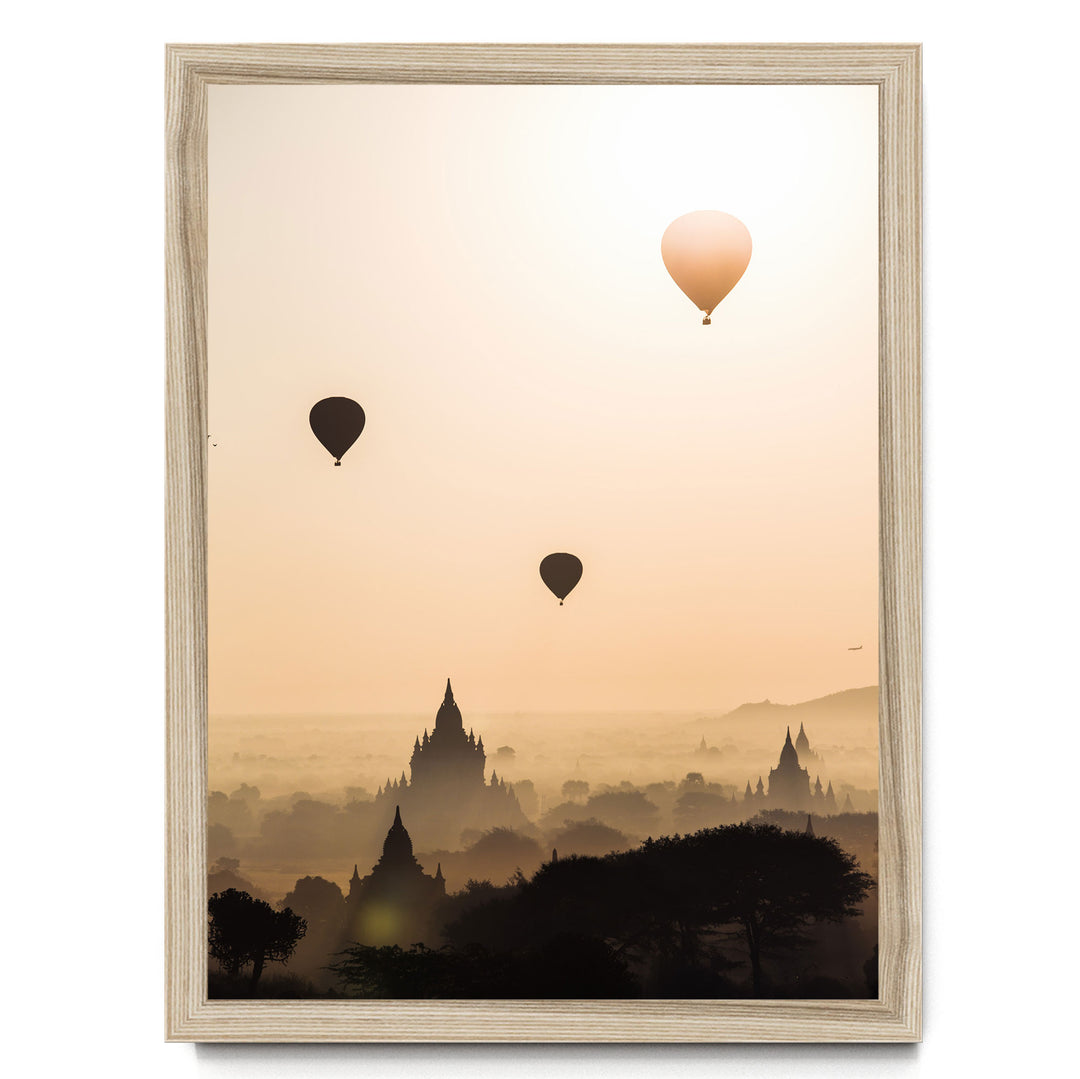 three hot air balloons floating in the sky above a cityscape with silhouetted buildings.