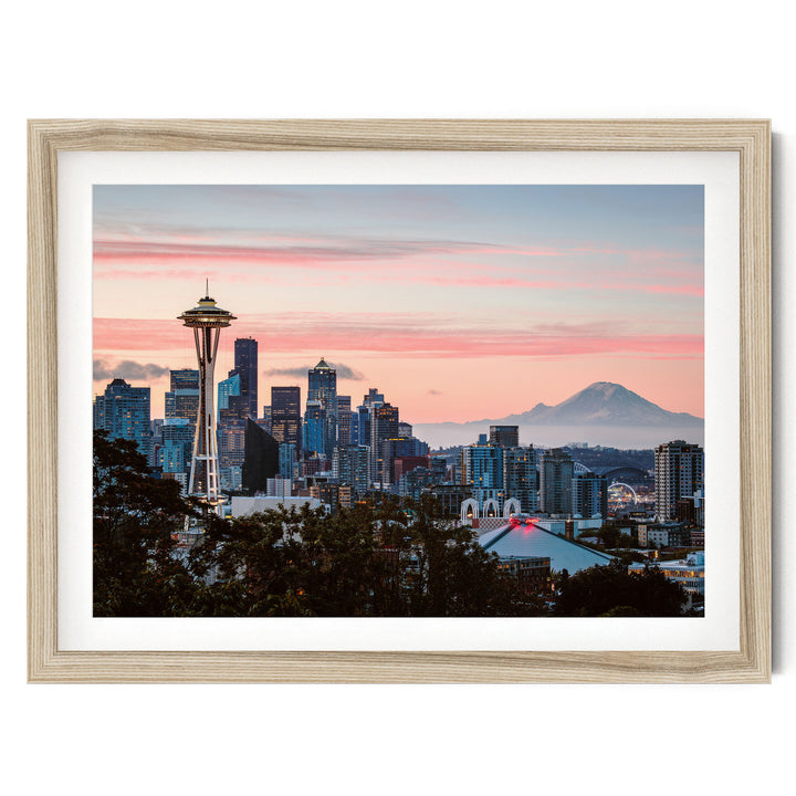 a city skyline at sunset, with the Space Needle and other buildings silhouetted against a vibrant pink and orange sky.