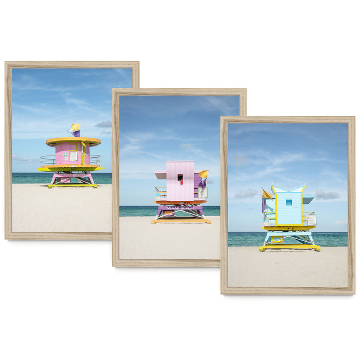 A collage of three beach lifeguard towers in different colors, including pink, yellow, and blue, set against a backdrop of a clear blue sky and the ocean.