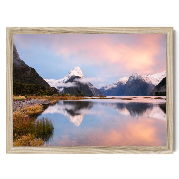 a serene landscape with a calm lake reflecting the surrounding mountains and sky. The mountains are covered in snow, and the sky is a beautiful gradient of pink and orange hues, creating a stunning backdrop for the scene. The overall composition is balanced and harmonious, showcasing the natural beauty of the landscape.