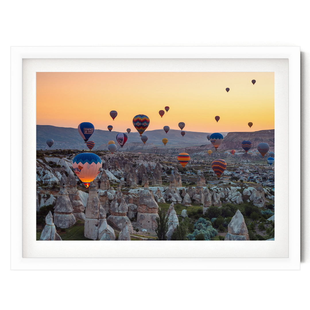 a breathtaking scene of hot air balloons floating over a mountainous landscape at sunset.
