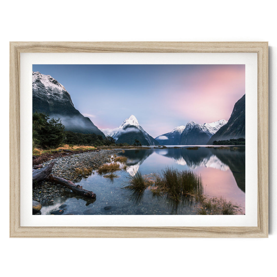 a serene landscape with a mountain range reflected in a calm lake, surrounded by lush vegetation and a clear blue sky.