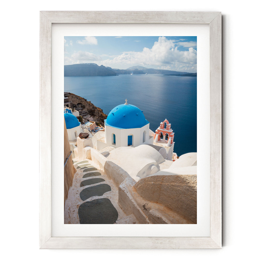 a picturesque view of a Greek island with white buildings and blue domes overlooking the sea.
