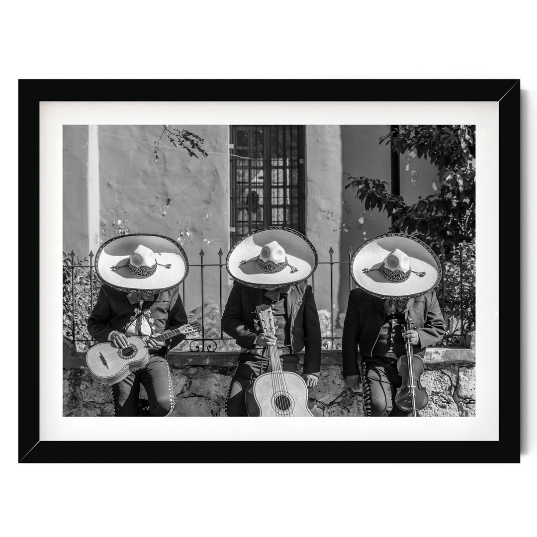 Three musicians wearing sombreros and playing guitar and maracas, arranged in a row, with a stone wall and window in the background.