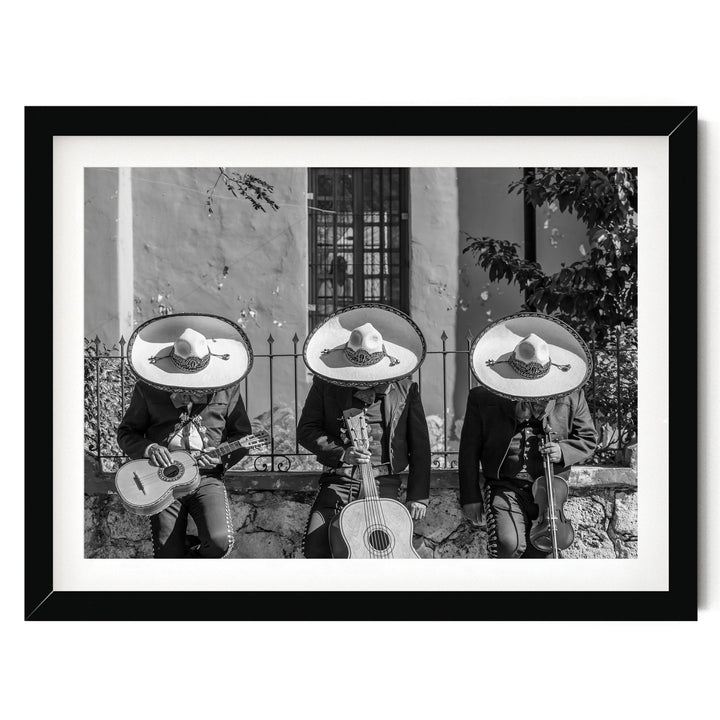 Three musicians wearing sombreros and playing guitar and maracas, arranged in a row, with a stone wall and window in the background.