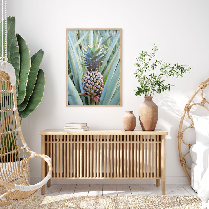 a modern and minimalist living room with a wooden console table, a woven chair, and a framed photograph of a pineapple on the wall.