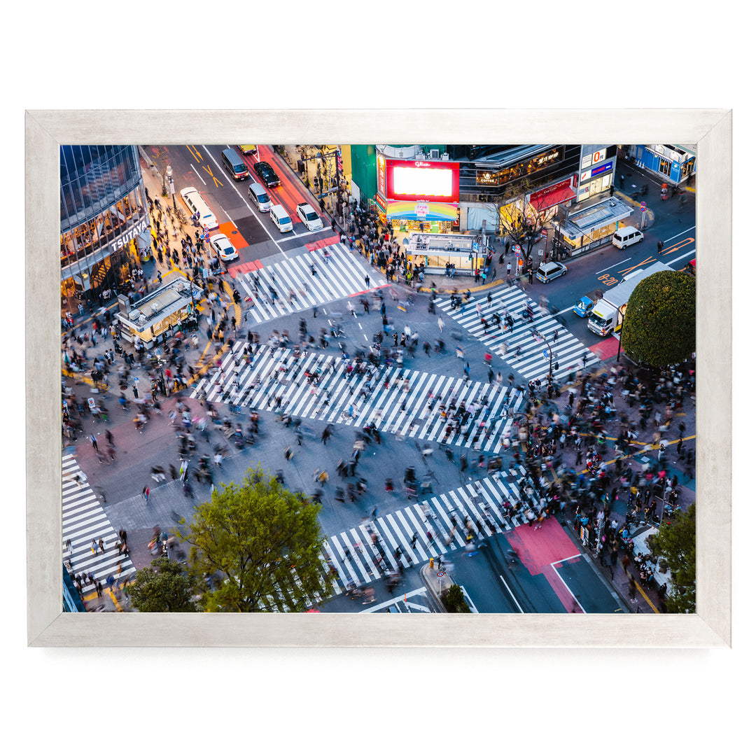 a busy city intersection with a large crowd of people crossing the street, surrounded by tall buildings and illuminated by colorful billboards.