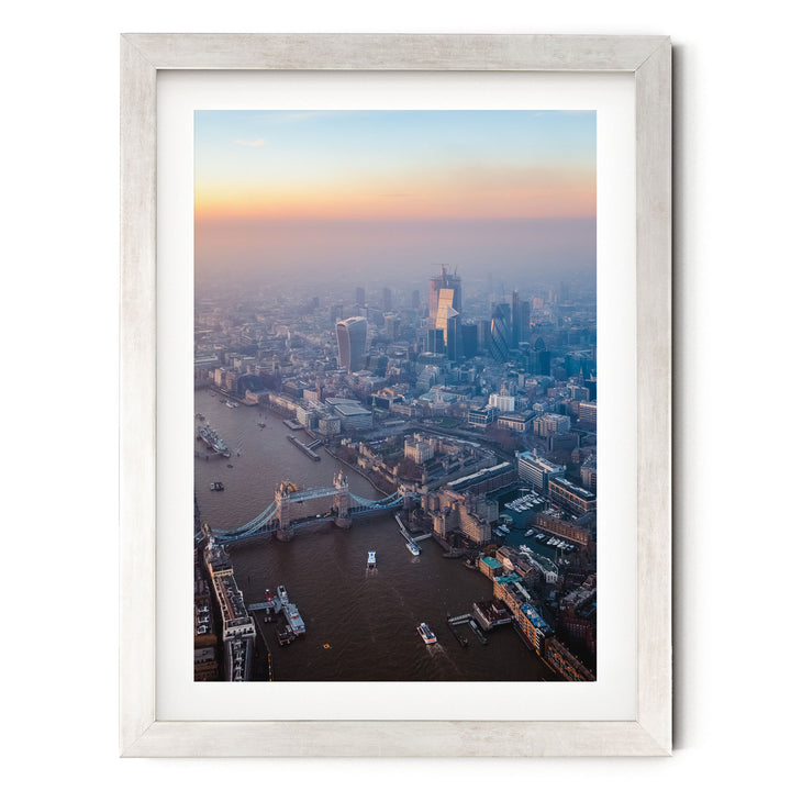 The image is an aerial view of a cityscape with a river running through it, featuring a bridge and several boats on the water.