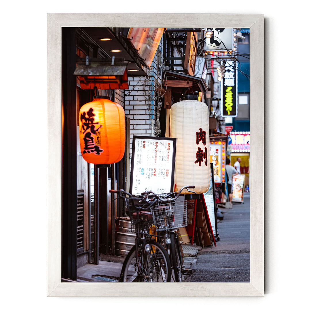 A bicycle parked on a street lined with colorful lanterns and signs, creating a vibrant and lively atmosphere.