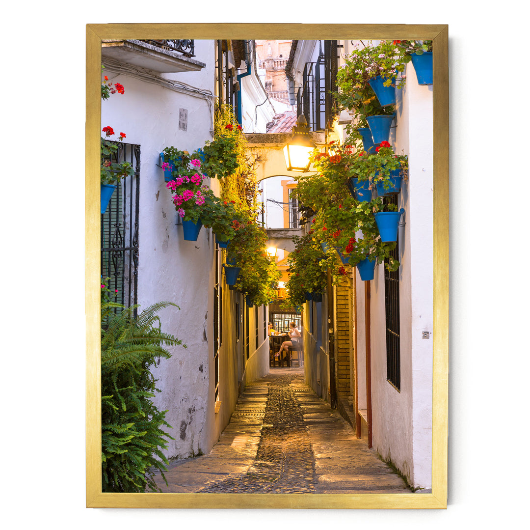 A narrow, cobblestone street lined with colorful flower pots and plants, creating a charming and picturesque scene.
