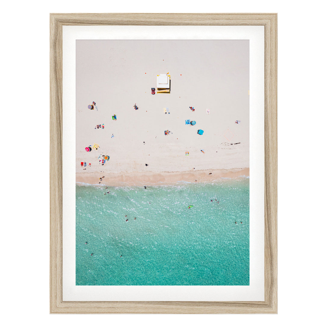 a beach scene with people enjoying the sun and water, with a small structure or object visible in the center of the frame.