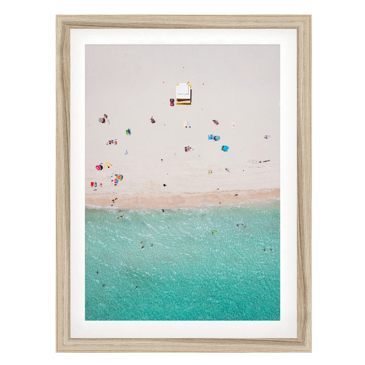 a beach scene with people enjoying the sun and water, with a small structure or object visible in the center of the frame.