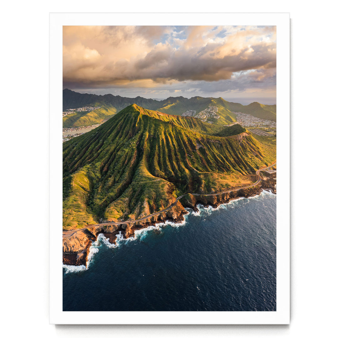 a stunning mountainous coastline with a winding road leading to the ocean. The landscape is covered in lush greenery, and the sky is filled with clouds, creating a dramatic backdrop. The overall scene is visually striking and captures the beauty of nature.
