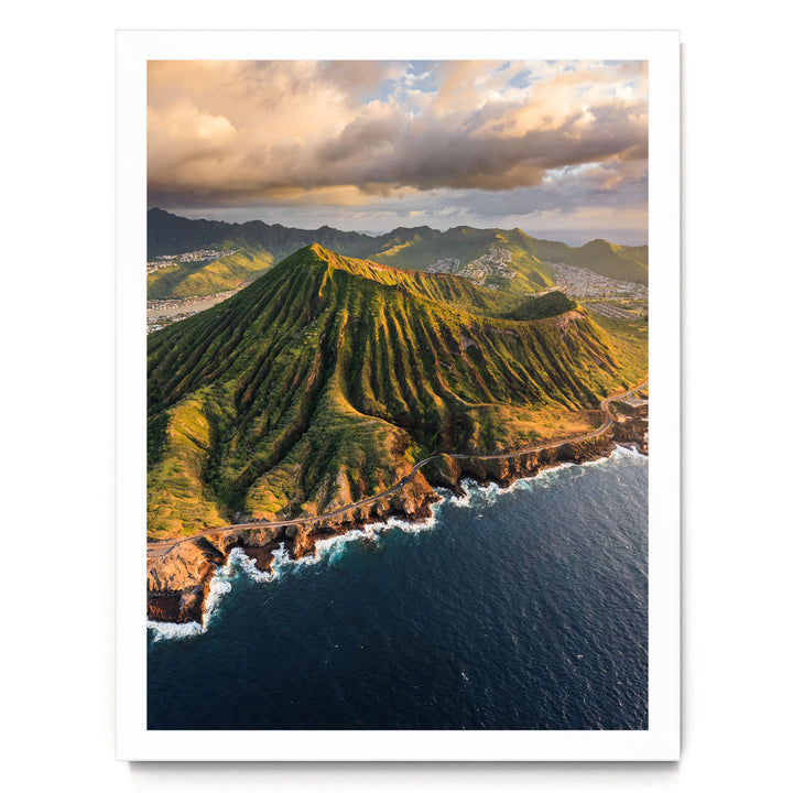 a stunning mountainous coastline with a winding road leading to the ocean. The landscape is covered in lush greenery, and the sky is filled with clouds, creating a dramatic backdrop. The overall scene is visually striking and captures the beauty of nature.