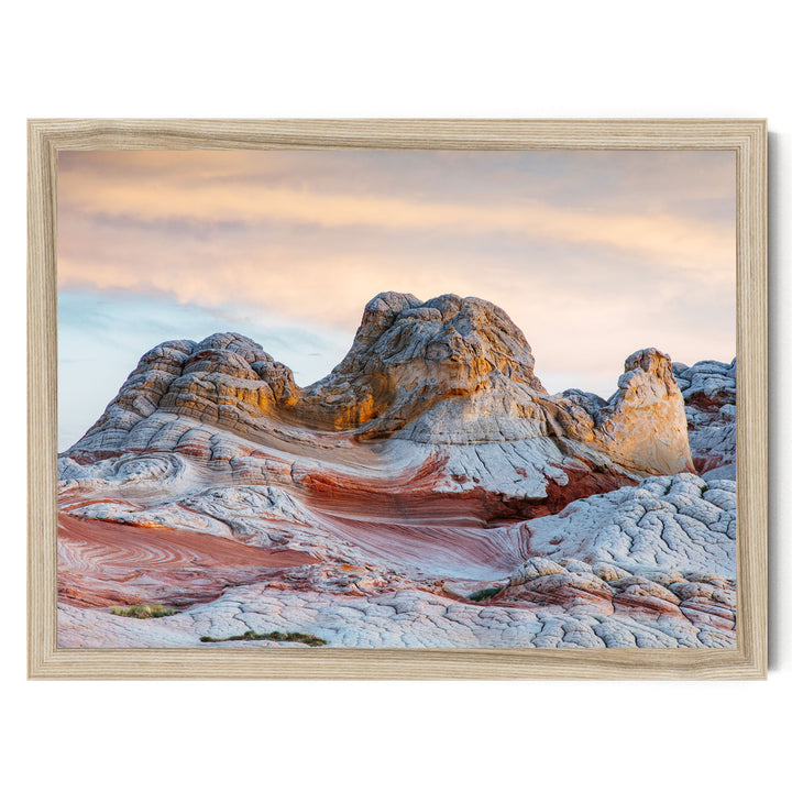 a striking natural landscape with a large, multi-layered rock formation in the foreground, set against a backdrop of a cloudy sky.