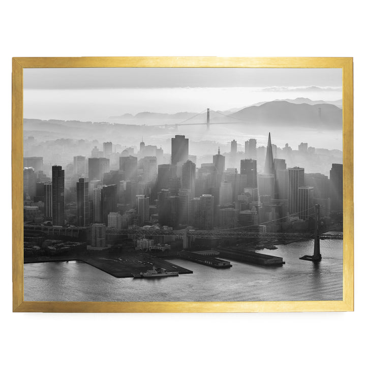 A black and white aerial view of a densely populated city skyline, with the Golden Gate Bridge visible in the distance.