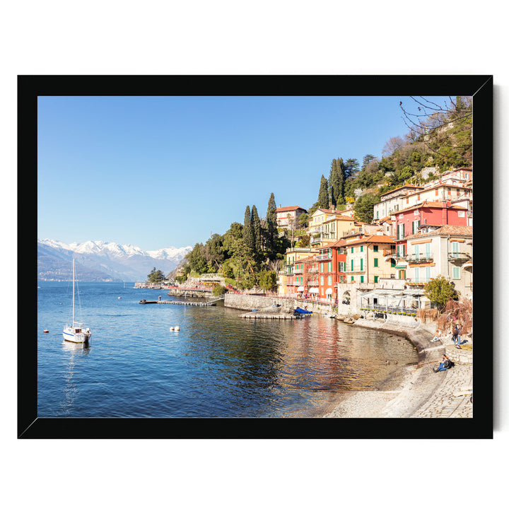 A picturesque coastal town with colorful buildings, a harbor, and a sailboat on the water, set against a backdrop of snow-capped mountains.