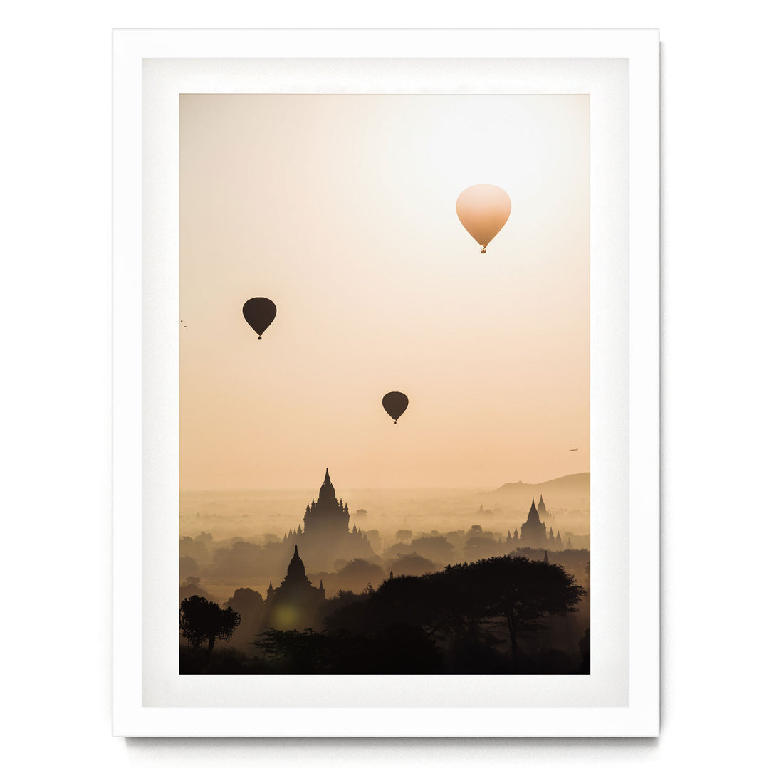 three hot air balloons floating in the sky above a cityscape with silhouetted buildings.