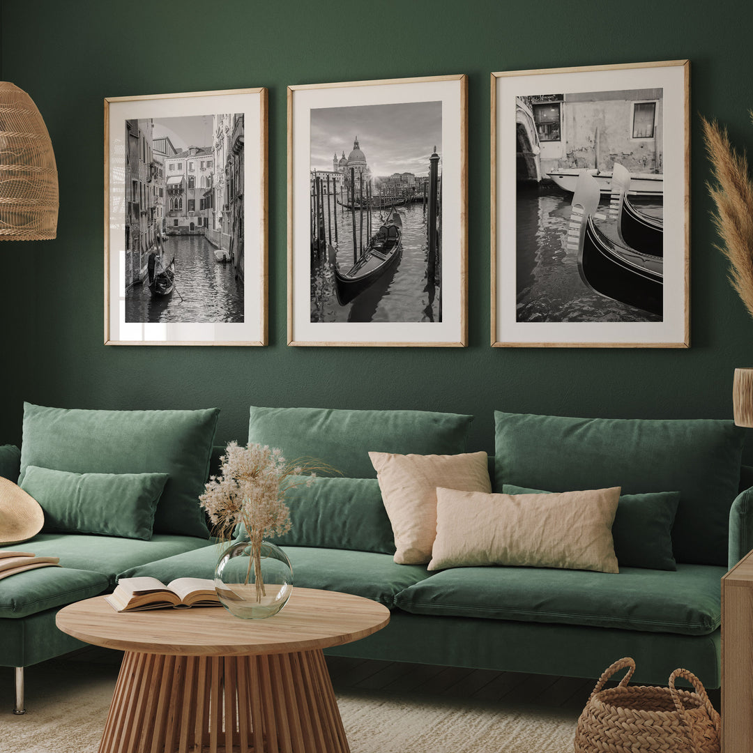 a living room with a green sofa, a wooden coffee table, and three framed black and white photographs of Venice canal scenes hanging on the wall.
