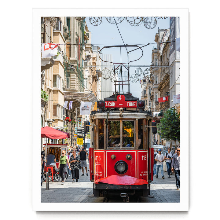 A red trolley car is traveling down a busy street in Istanbul, Turkey, surrounded by pedestrians and buildings.