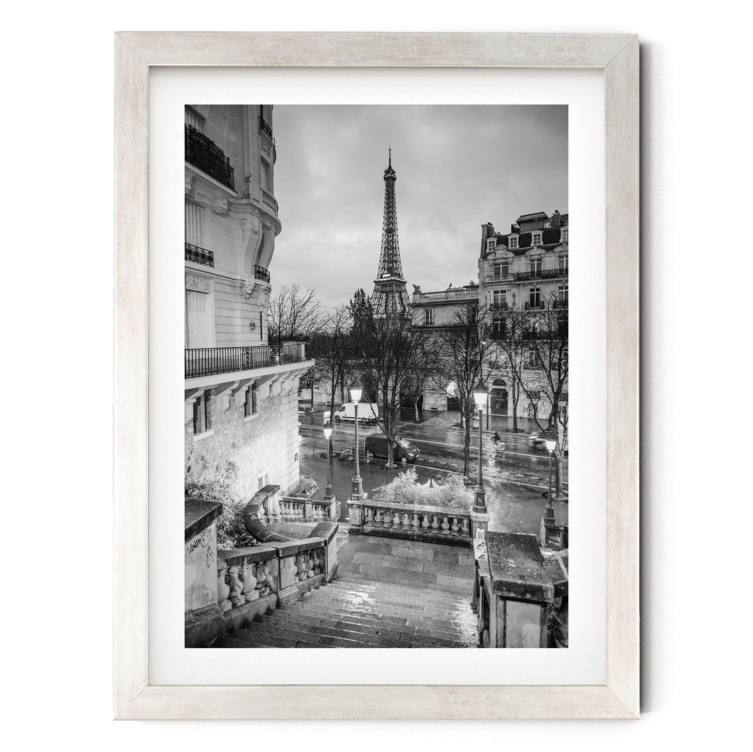 A black and white photograph of the Eiffel Tower in Paris, France, with the surrounding buildings and streets visible.