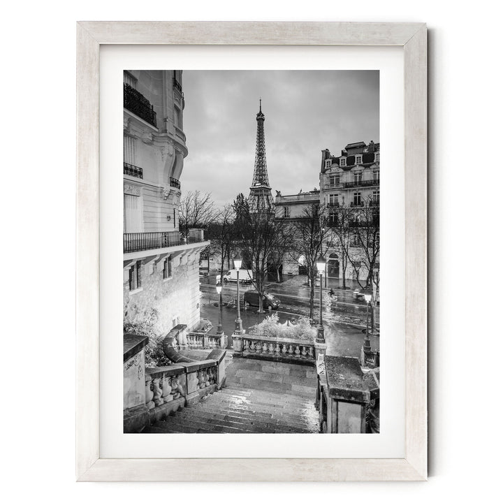 A black and white photograph of the Eiffel Tower in Paris, France, with the surrounding buildings and streets visible.