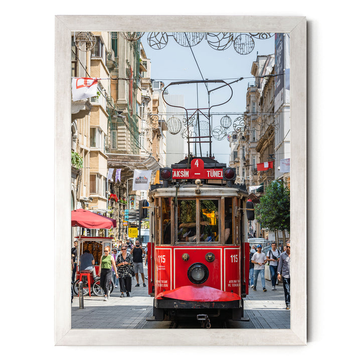A red trolley car is traveling down a busy street in Istanbul, Turkey, surrounded by pedestrians and other vehicles.