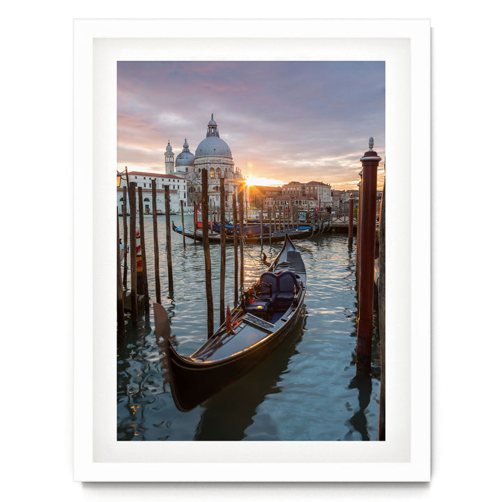 a serene scene of a gondola floating on the water, with a picturesque view of the city skyline and the sun setting in the background.