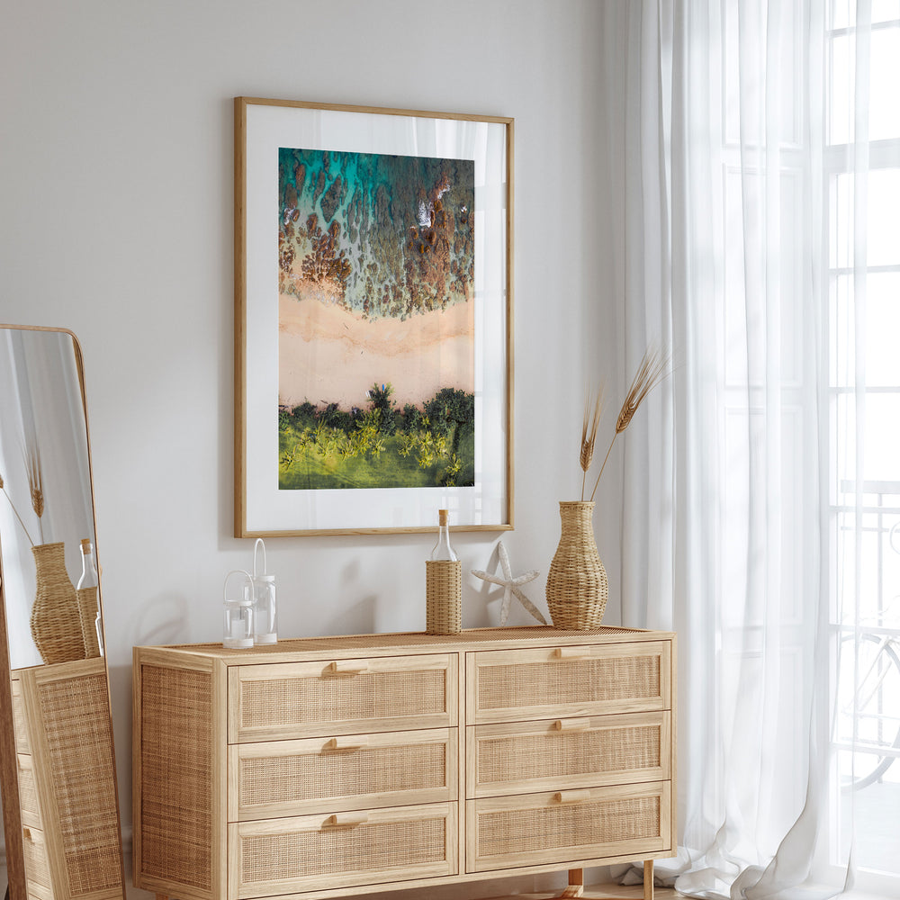 a wooden dresser with a framed picture of a beach scene hanging above it. The dresser has six drawers and is situated in a room with a window and a mirror.