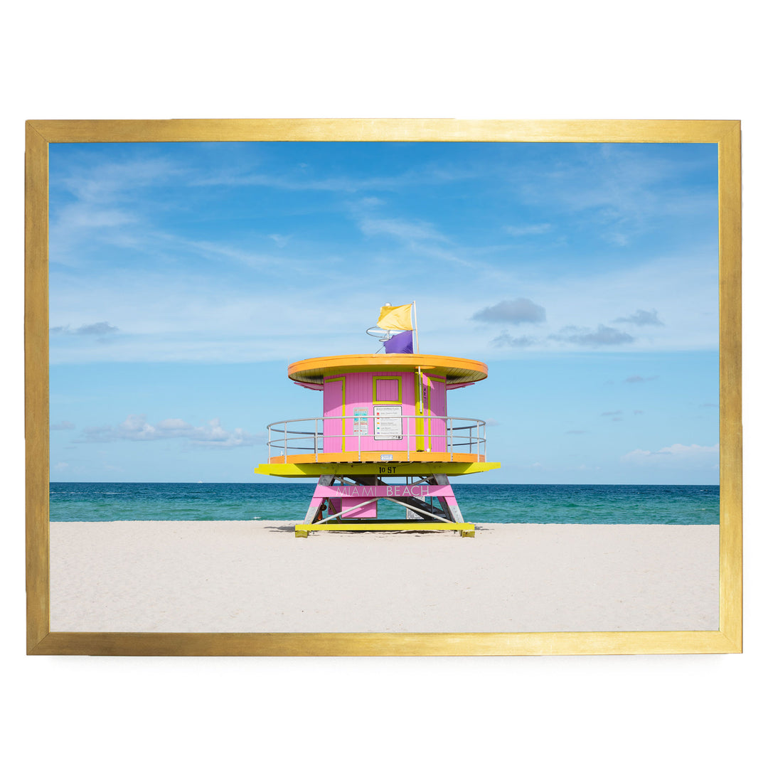 A brightly colored lifeguard tower stands on a sandy beach, with the ocean visible in the background.