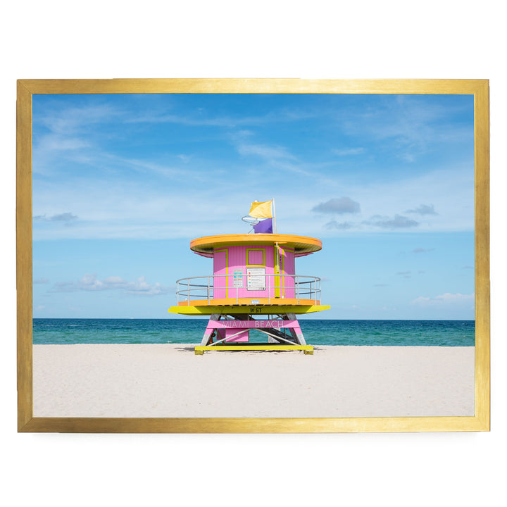 A brightly colored lifeguard tower stands on a sandy beach, with the ocean visible in the background.