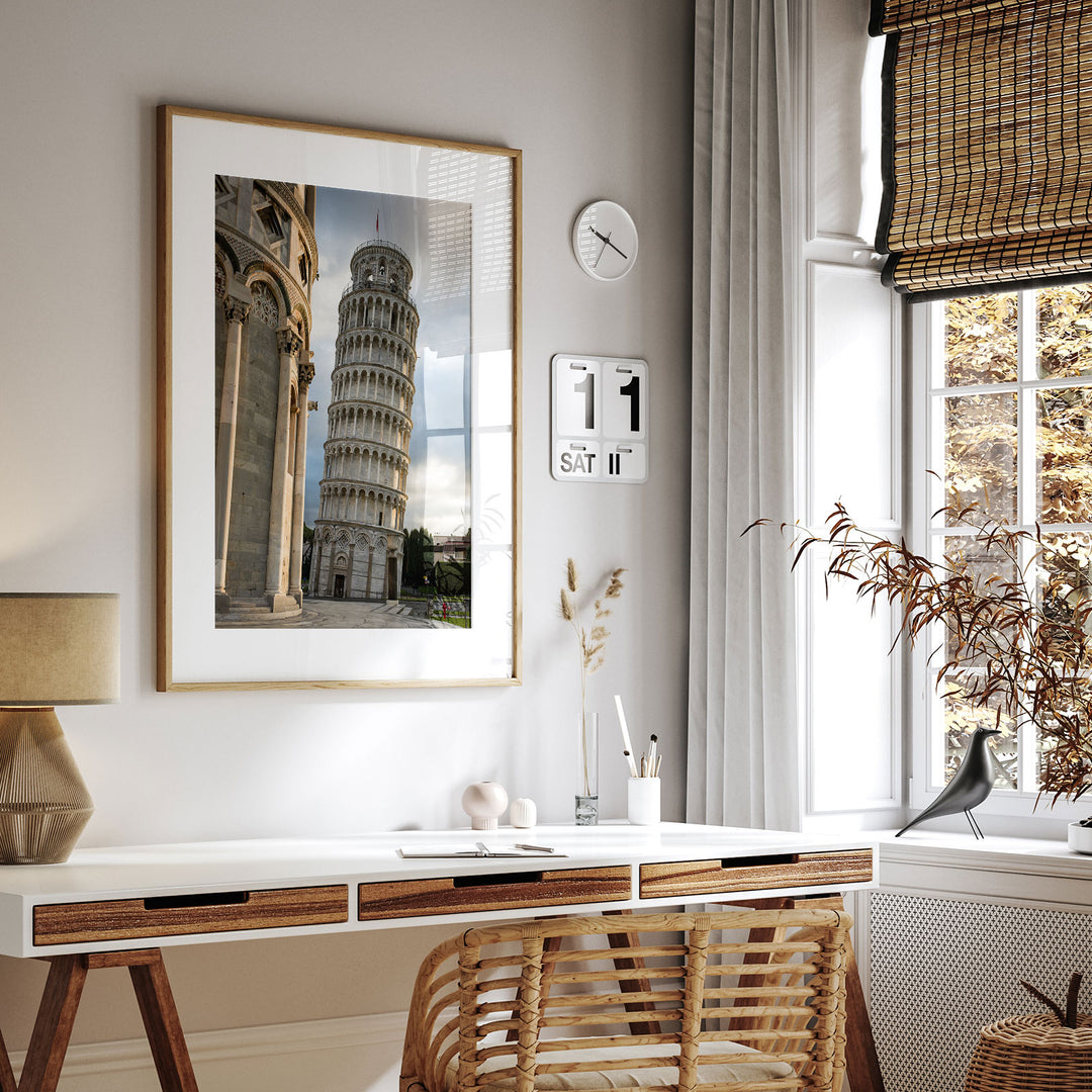 Framed Leaning Tower of Pisa print above a desk in a bright home office