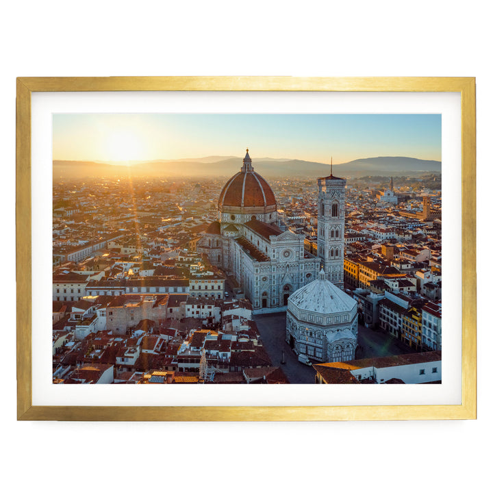 a cityscape with a large dome-shaped building, possibly a church or a government building, surrounded by a densely populated urban area with numerous other buildings. The sun is setting, casting a warm glow over the scene and creating a picturesque atmosphere.