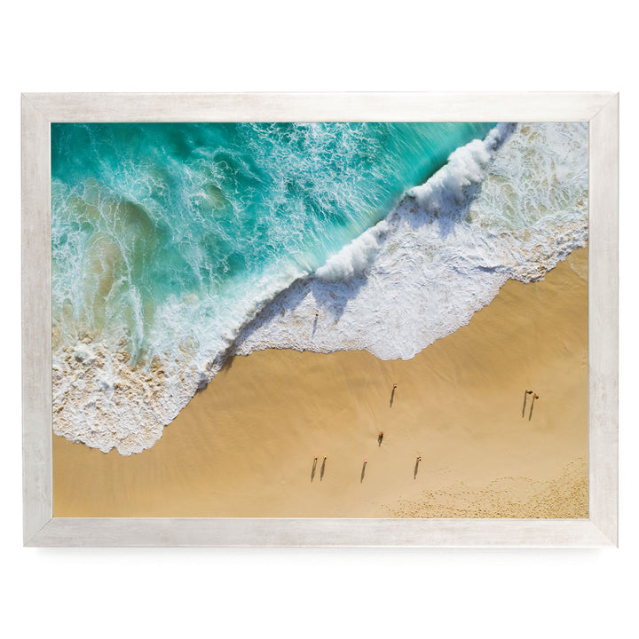 a serene beach scene with a large wave crashing onto the sandy shore, where a group of people are walking along the beach.