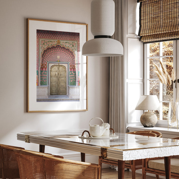 a dining room with a white table and chairs, a framed picture of a colorful doorway, and a hanging lamp.