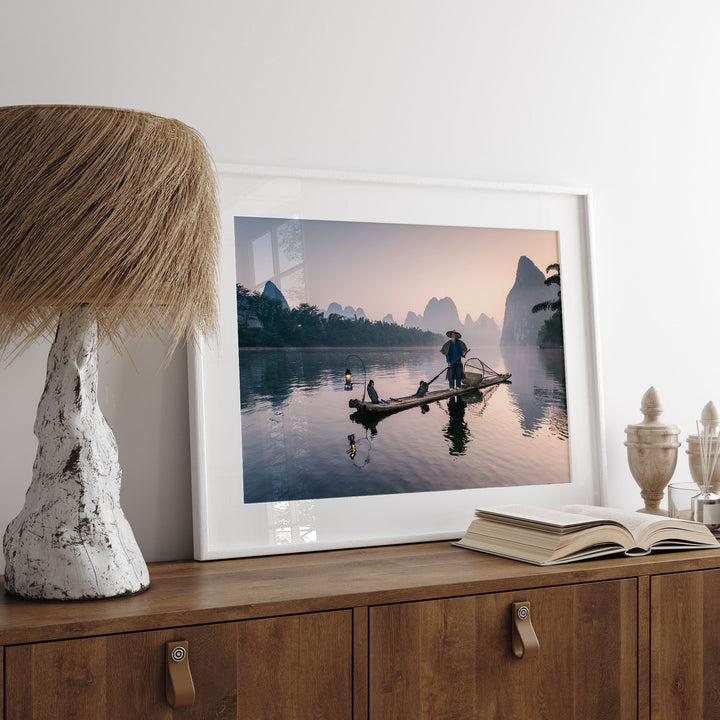 a framed photograph of a person rowing a boat on a river, with a serene landscape in the background.