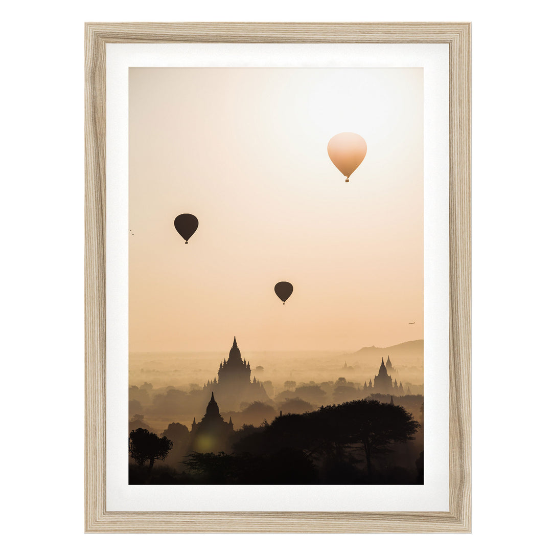 three hot air balloons floating in the sky above a cityscape with silhouetted buildings.