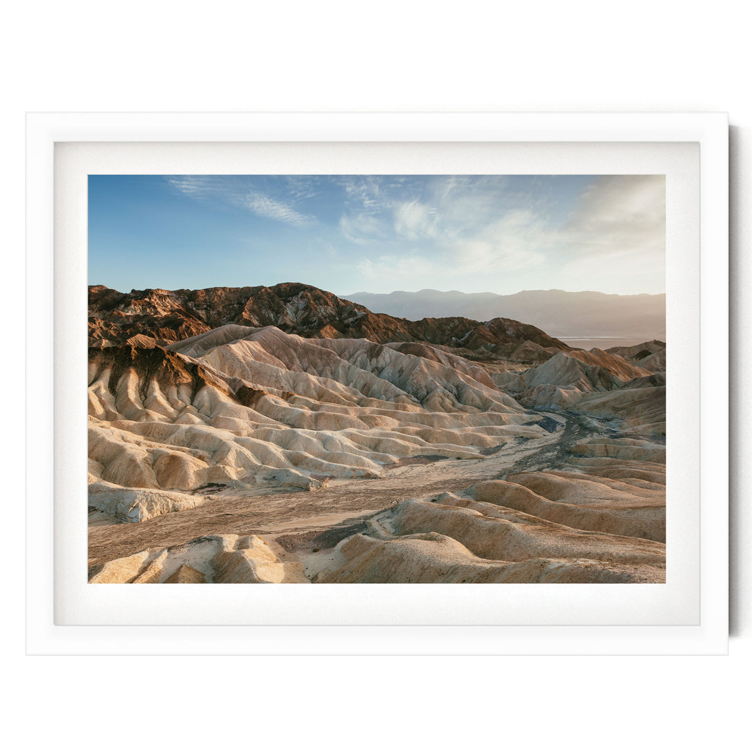 a vast, rugged landscape with rolling hills and mountains in the background, set against a clear blue sky.