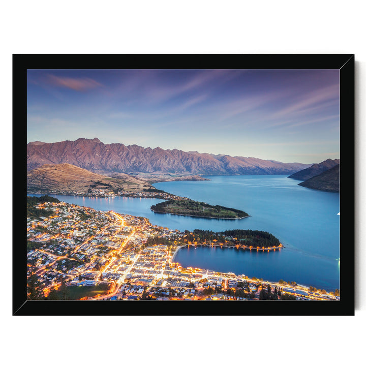 a picturesque city nestled at the foot of a mountain range, with a stunning view of the city lights reflected in the calm waters of the lake or river.